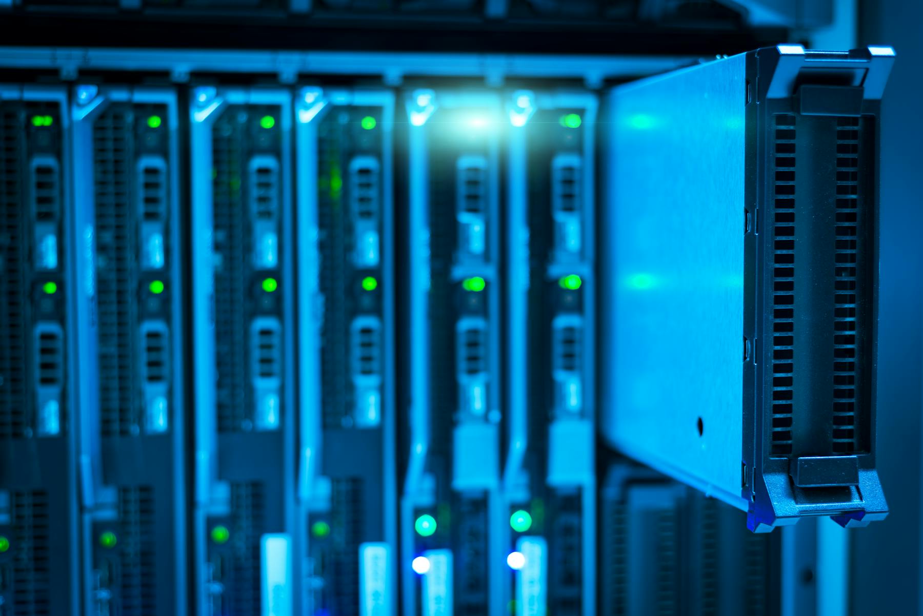 Illuminated data-center racks viewed through a narrow corridor.