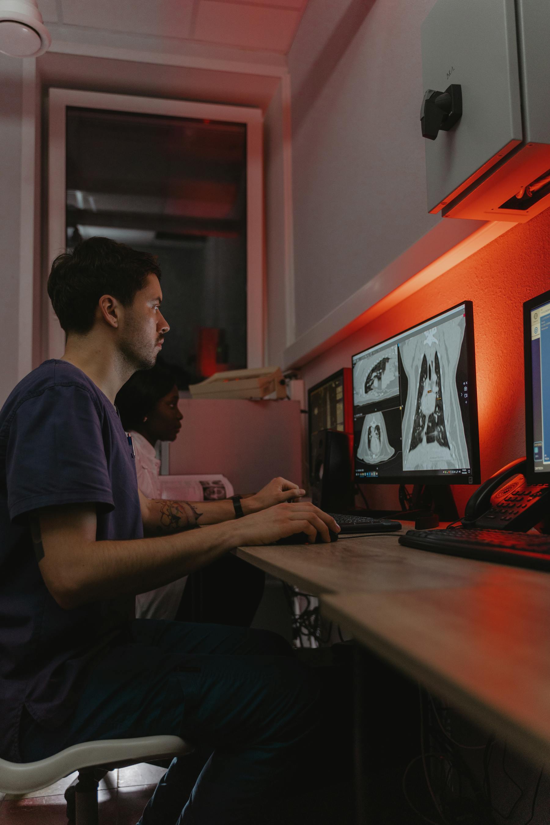 Clinical researchers work under red laboratory light in a medical environment.