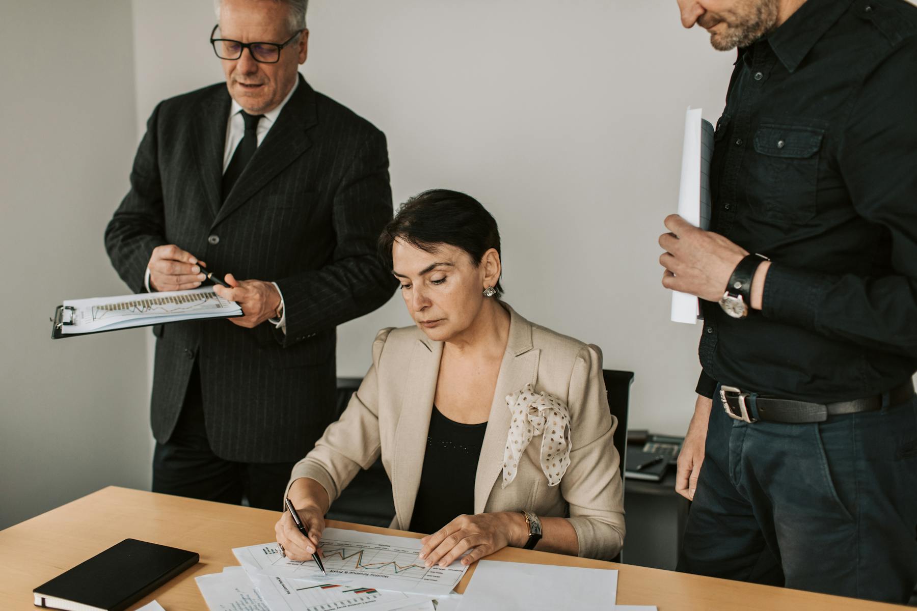 Business partners review documents around a conference table in a private office.